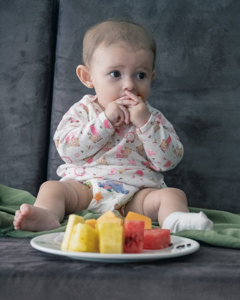 photo by felipe salgado baby in white and pink onesie sitting on green and white ceramic plate